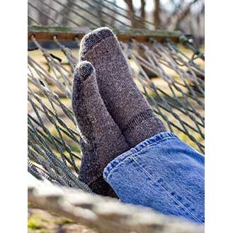 a photo of someone's feet wearing the alpaca survival sock while laying in a hammock on a sunny day