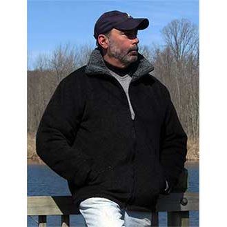 Man with cap wearing the alpaca barn jacket standing on a dock