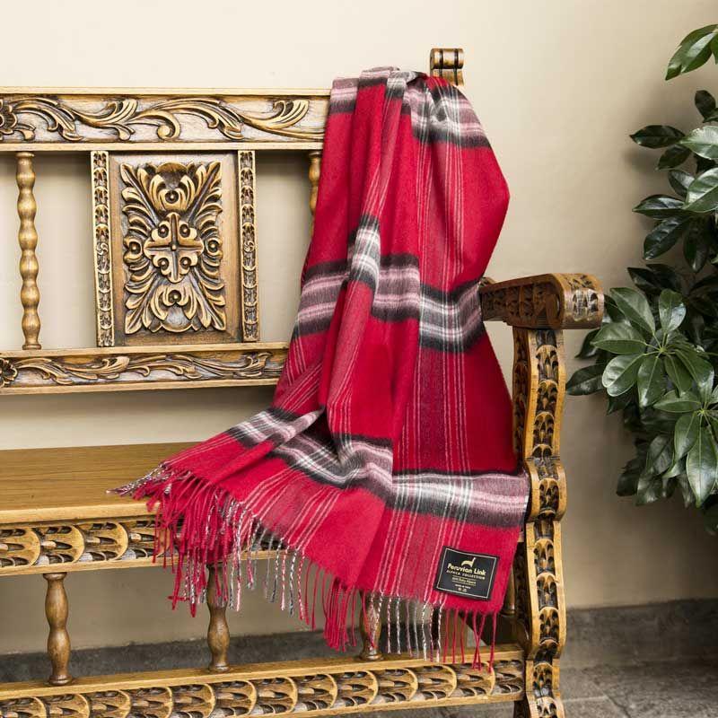 photo of a red plaid alpaca throw draped over a wooden bench that has intricate carving